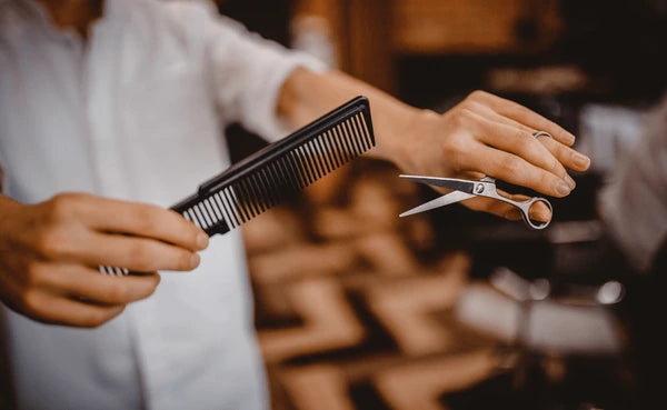 Professional barber cutting hair with comb and stainless steel scissors in salon by Styleup Beauty Tools